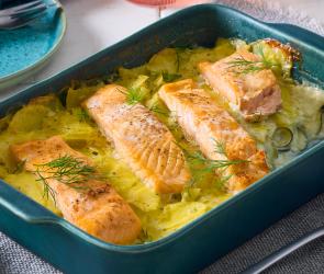 Kartoffel-Zucchini-Auflauf mit Lachs in einer blauen Auflaufform auf einem Tisch.