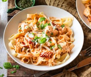 Fettuccine mit Hähnchen und getrockneten Tomaten in Schüsseln.