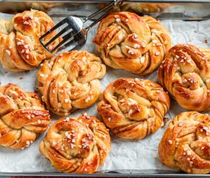 Schwedische Zimtknoten (Kanelbullar) auf einem Blech mit Backpapier.