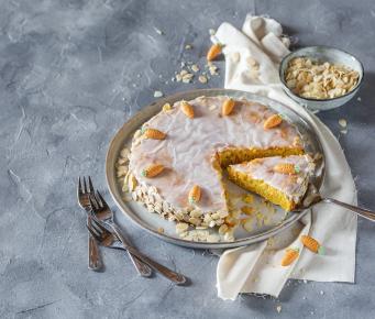 Karottenkuchen mit Zuckerguss auf einem Servierteller.