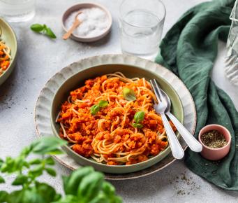 Rote Linsen-Bolognese mit Spaghetti in einem tiefen Teller.