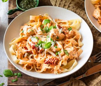 Fettuccine mit Hähnchen und getrockneten Tomaten in Schüsseln.