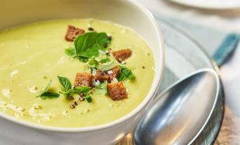 Zucchini-Kartoffel-Suppe in einem Teller mit Brotcroûtons garniert.