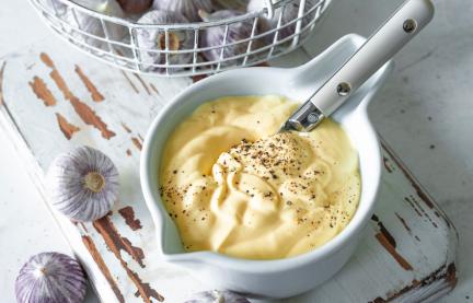 Schüsselchen mit Aioli und Knoblauchzehen im Körbchen.