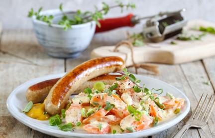 Bratwurst mit Rahm-Karotten auf einem Teller.