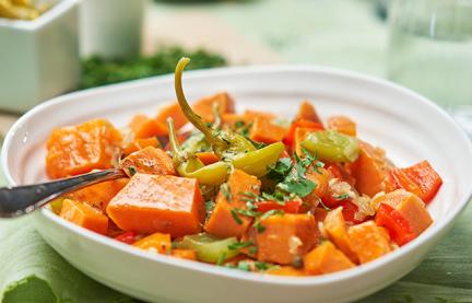 Eintopf aus Süßkartoffelwürfeln und Paprika auf Teller.