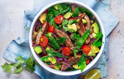 Gebratene Rinderfiletstreifen mit Tomaten und Zuckerschoten in einem tiefen Teller angerichtet.