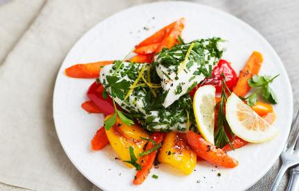 Gedämpftes Zitronen-Kräuter-Hähnchen auf Gemüse auf einem Teller serviert.