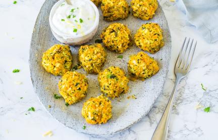 Elf Gemüsebällchen auf Teller mit Joghurt-Dip.