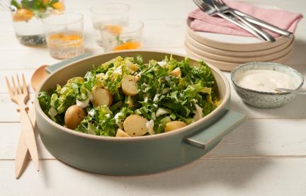 Grüner Salat mit kleinen Kartoffeln und Orangen-Sahne-Dressing in einer Schale.