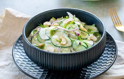 Gurkensalat mit Sellerie in einer Schüssel auf einem Tisch.