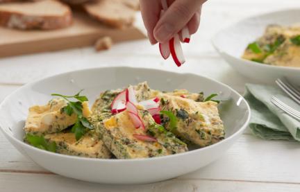 Käse-Kräuter-Omelett in Stücken mit Radieschen in einem Teller.