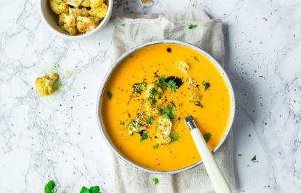 Karotten mit Sesam-Blumenkohl-Topping in einer Schüssel angerichtet.