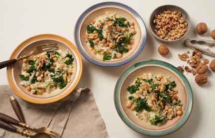 Kohlrabi mit Blattspinat und Kichererbsen in drei Tellern auf einem Tisch.