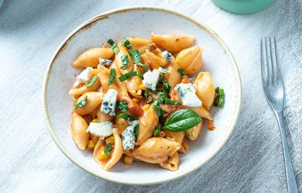 One-Pot-Pasta mit Tomaten, Mais und Blauschimmelkäse in einem Teller.