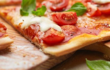 Pizza Margherita angeschnitten auf einem Holzbrett.