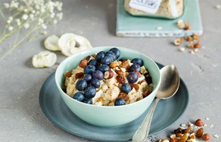 Glas mit Porridge-Mischung für den Cookit, davor fertiges Porridge in Schüssel.