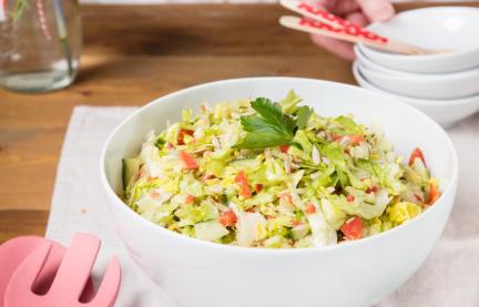 Eisbergsalat mit Gemüse in großer weißer Schüssel.