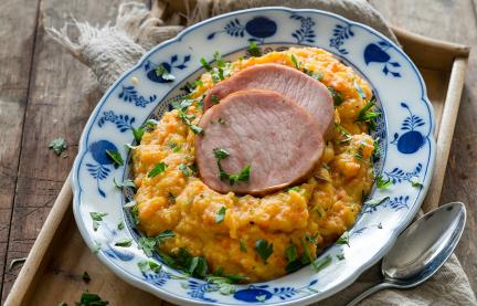 Steckrübenmus mit Kasseler auf einem Teller angerichtet.