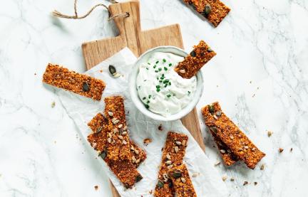 Mehrere Tomaten-Karotten-Cracker mit Pesto auf Schiefertafel.