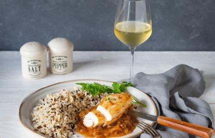 Hähnchen und Reis auf Teller mit Besteck, Weinglas und Tuch