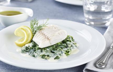 Zanderfilet gedämpft mit cremigem Blattspinat auf einem Teller.