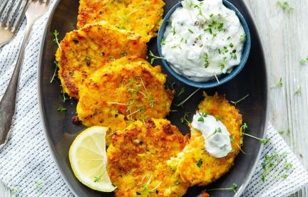 Gemüse-Kartoffel-Puffer mit Kräuterdip auf einem Teller.