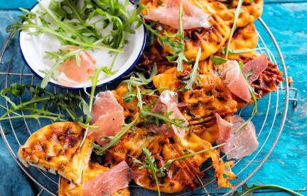Schnelle Pizzawaffeln auf einem Gitter mit Schinken und Rucola.