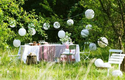 Mittsommerfest im Freien mit Tischen, Stühlen und Girlanden.