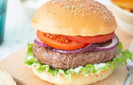 Hamburger mit Tomaten auf einem Bettchen.
