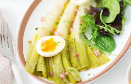 Lauchsalat mit Himbeer-Vinaigrette und zwei halbe Eier auf einem Servierteller.