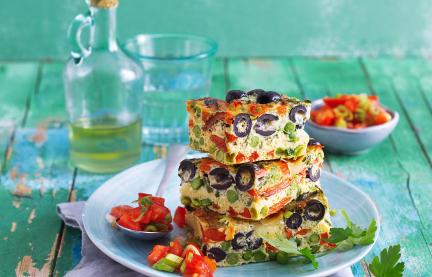 Frittata mit Tomatensalat auf einem Teller gestapelt.