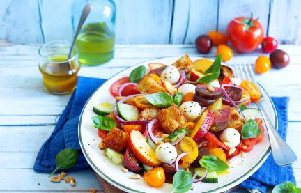 Panzanella mit bunten Tomaten, Mozzarella und Nektarinen auf einem Teller.