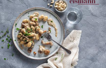 Gnocchi mit Pilzen und Sauce auf einem Teller.