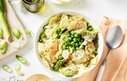 Nudeln, Erbsen und Hähnchen in Brühe in einer Schale.