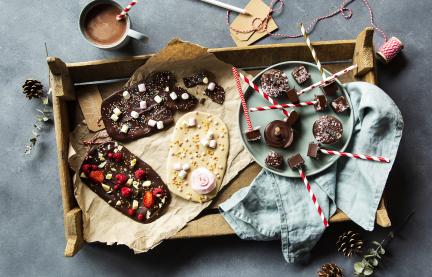 Bruchschokolade mit bunten Topping auf einem Holztablett.