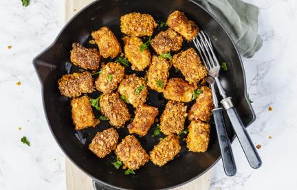 Tofu-Nuggets mit einer Pfanne. Daneben ein heller Dip.