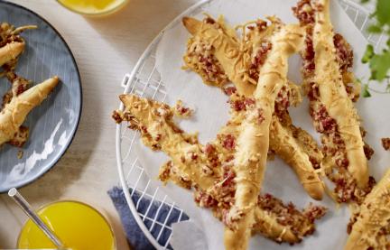 Knusprige Käsestangen mit kleinen Salamistücken.