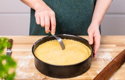 Gedeckter Apfelkuchen - Teig wird mit einer Gabel eingestochen.