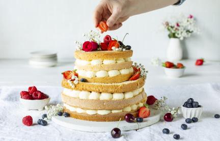 Hochzeitstorte wird mit Beeren dekoriert.