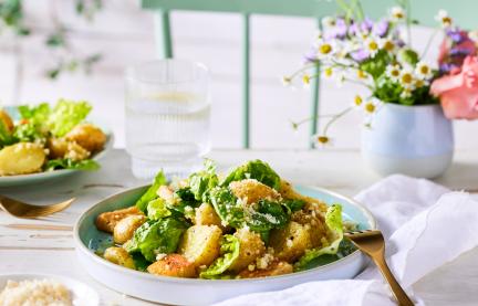 Caesar salad in Schüsseln auf einem gedeckten Tisch mit Blumen.