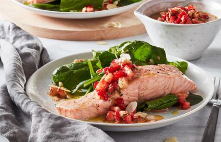 Lachs mit Spinat und Erdbeeren auf zwei Tellern angerichtet.