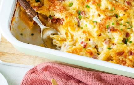 Cremiges Nudel-Schinken-Gratin auf Teller und in Auflaufform
