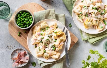 Tortellini mit Schinken und Erbsen auf Teller