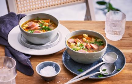 Gemüsesuppe mit Nudeln in Suppenschüsseln auf einem Tisch.