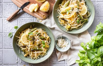 Spaghetti mit Zitronen und grünem Spargel in zwei tiefen Tellern.