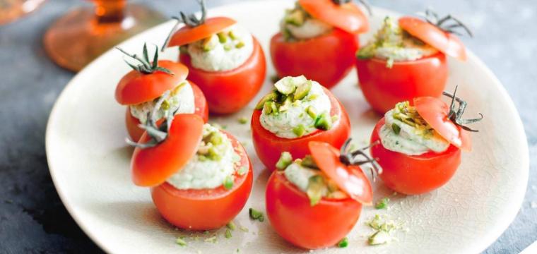 Kirschtomaten mit Basilikumcreme arrangiert auf einem weißen runden Teller