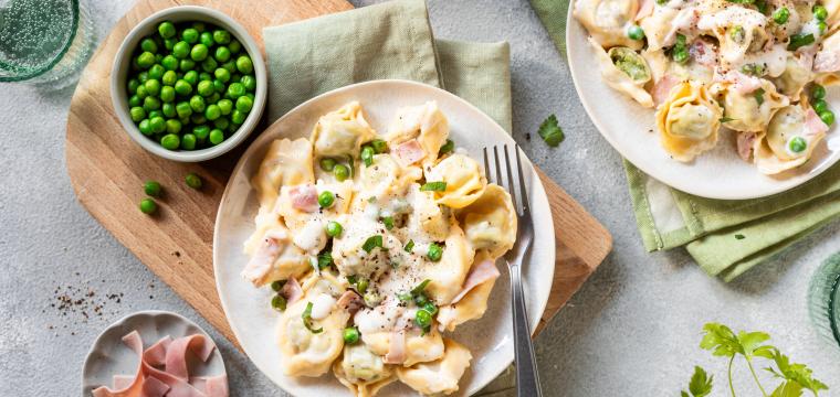 Tortellini mit Schinken und Erbsen auf Teller