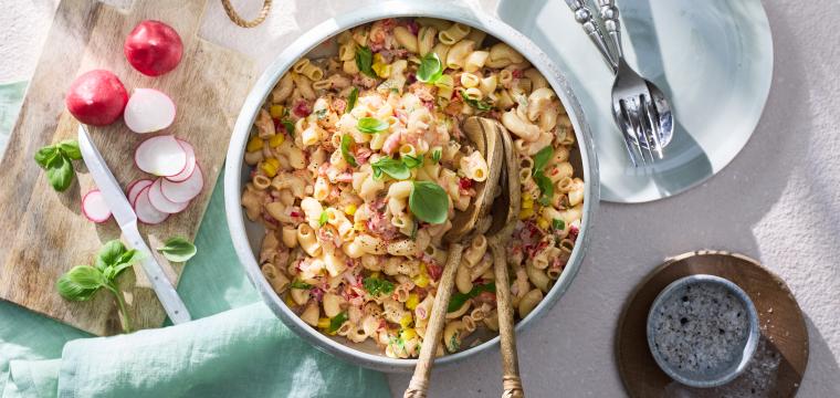 Nudelsalat in einer großen Schüssel mit Salatbesteck.