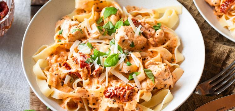 Fettuccine mit Hähnchen und getrockneten Tomaten in Schüsseln.